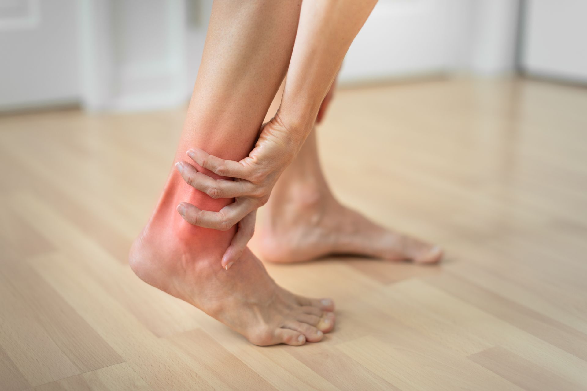 A woman is sitting on the ground with her legs crossed and stretching her feet.