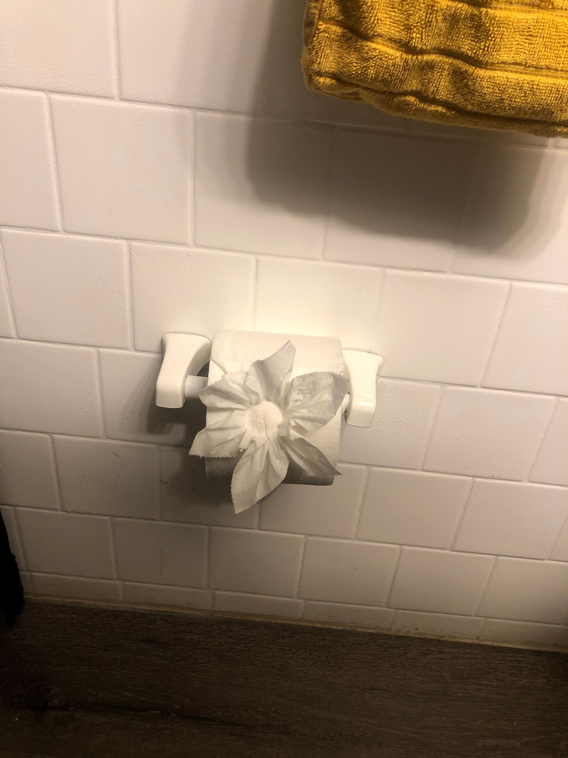 a roll of toilet paper in a bathroom with a yellow towel hanging on the wall .