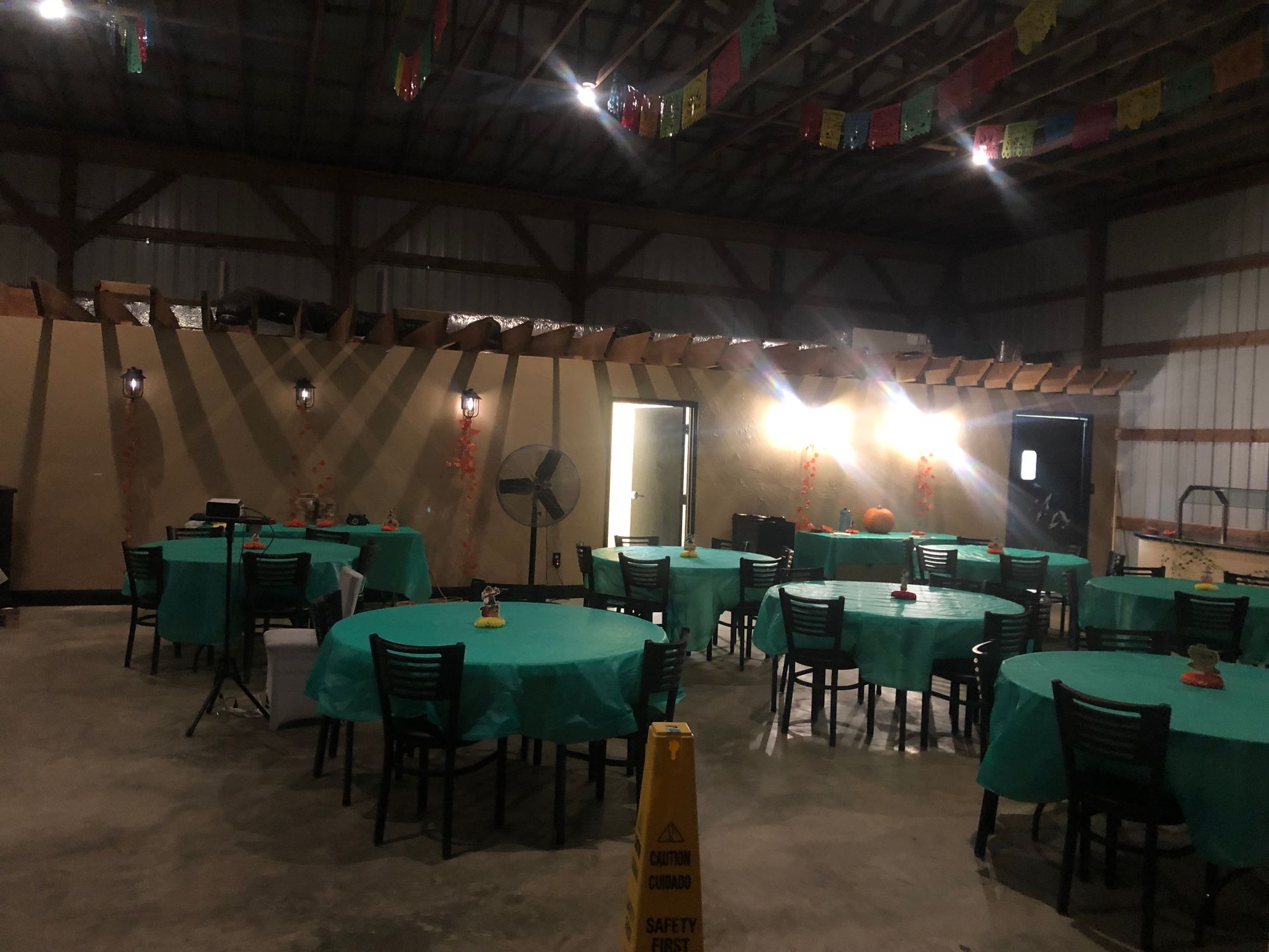 a large room with tables and chairs and a yellow wet floor sign