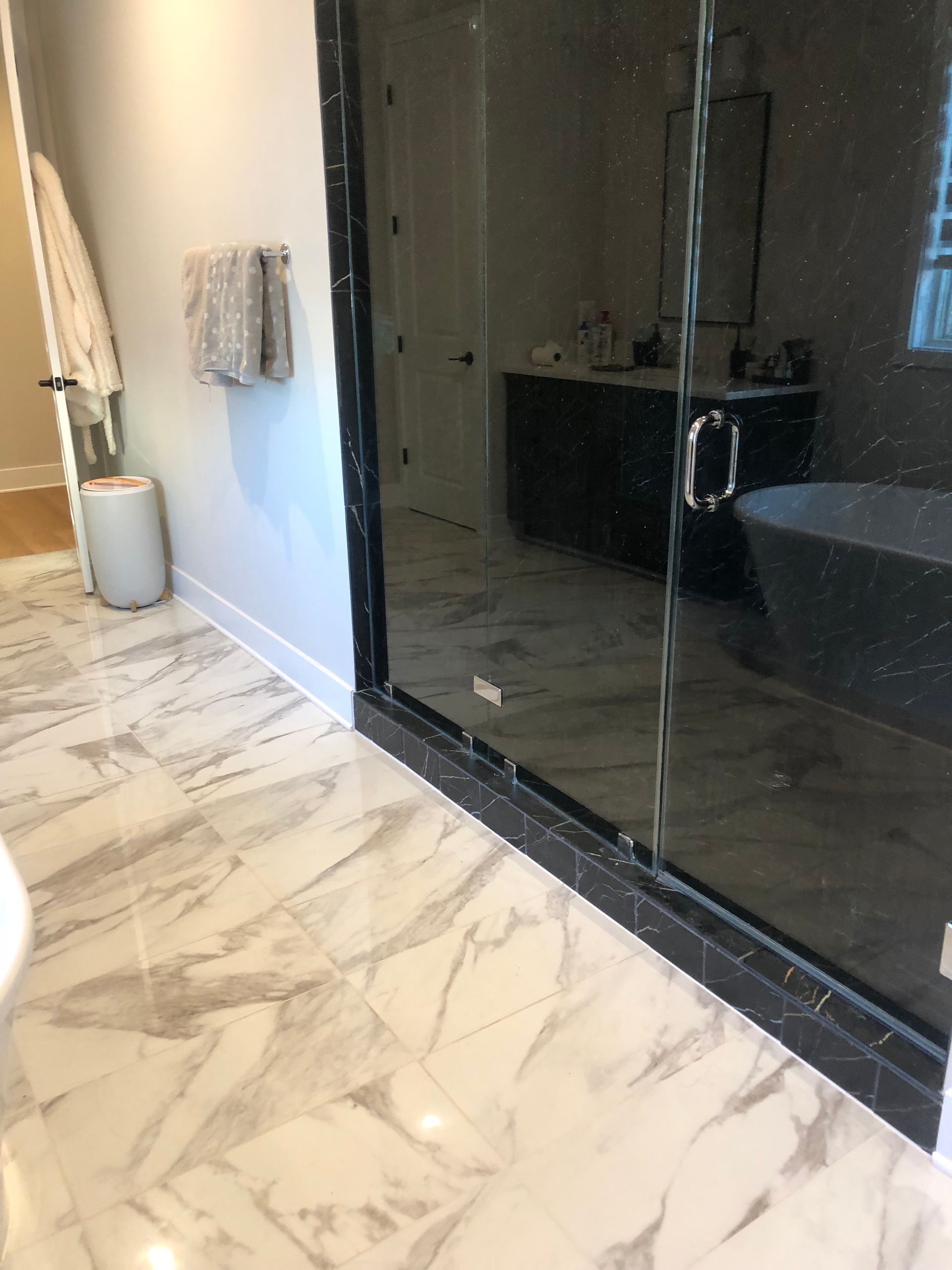 a bathroom with marble floors and a glass shower door .
