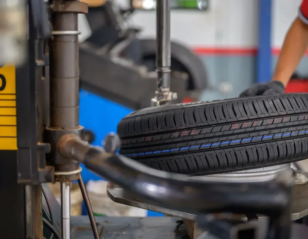 A person is changing a tire on a machine in a garage.