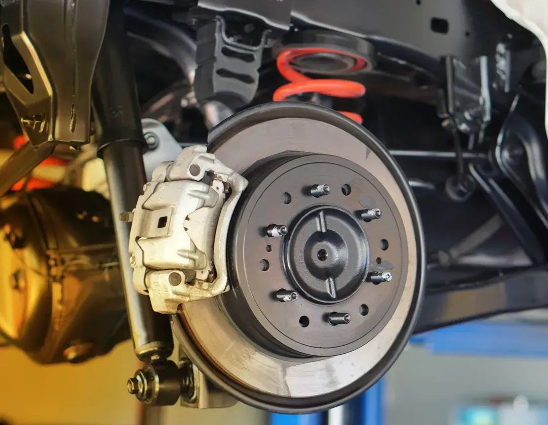 A close up of a car 's brake system on a lift.