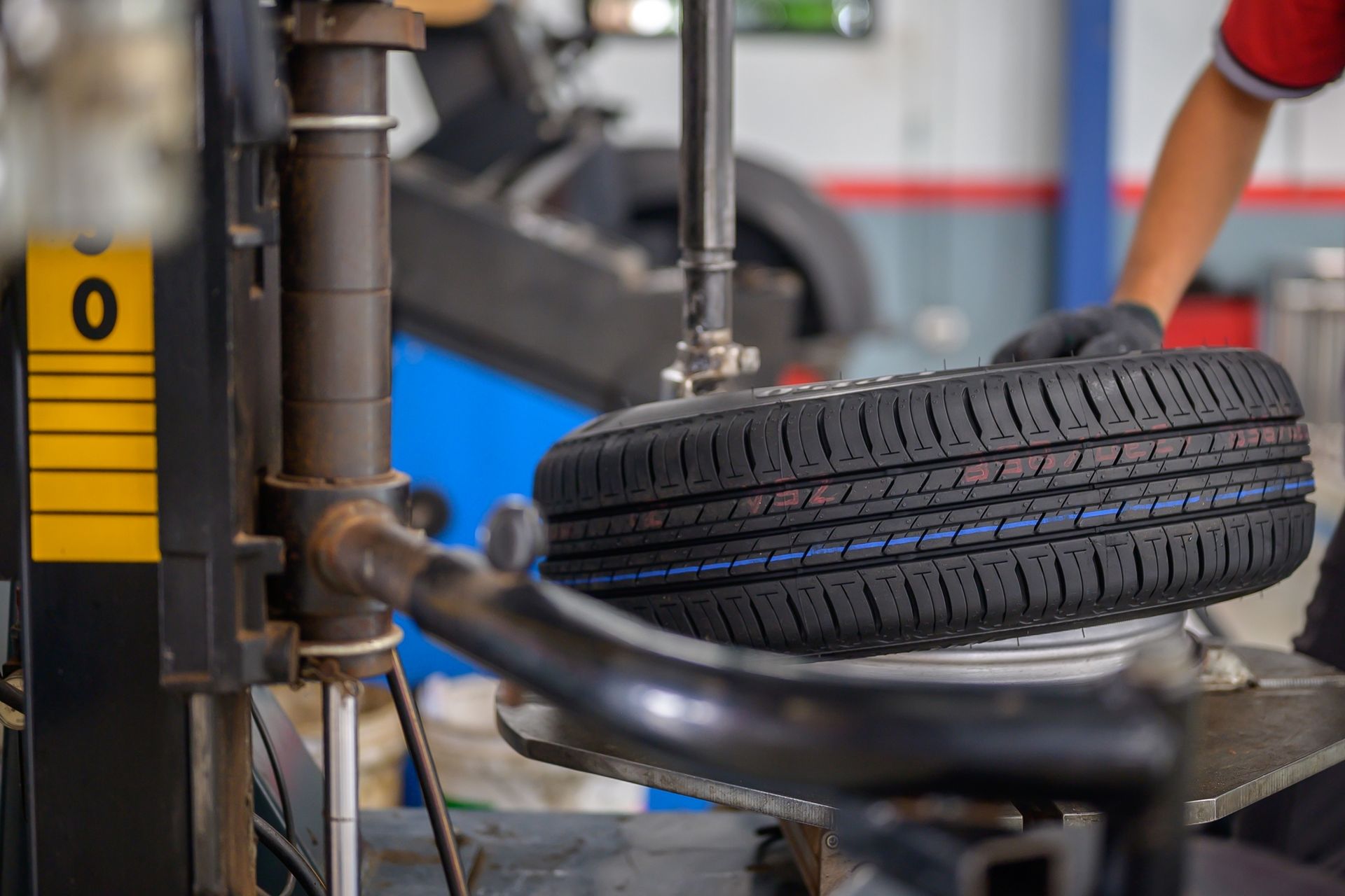 A person is changing a tire on a machine in a garage.