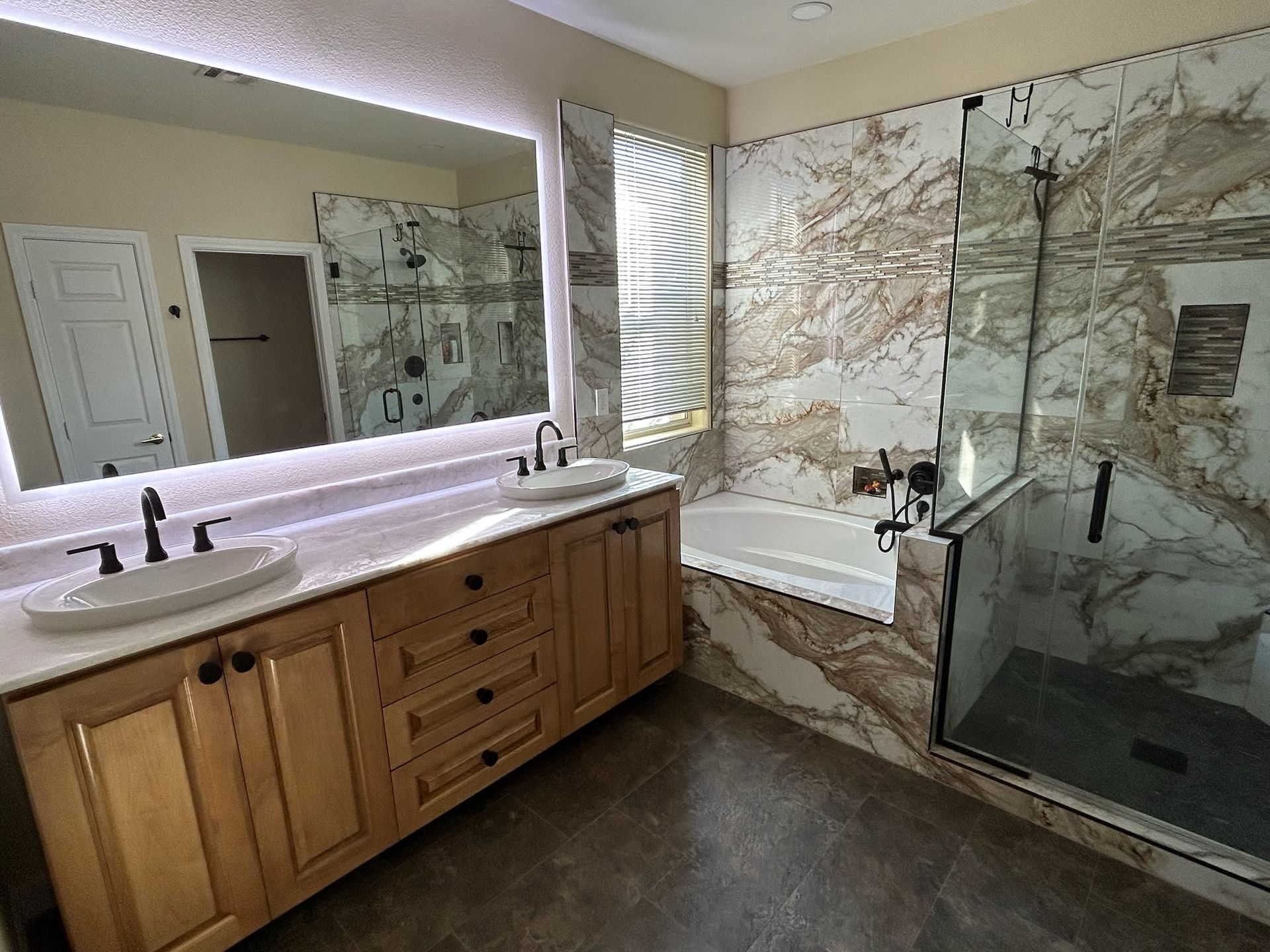 A bathroom with two sinks , a tub , a shower and a large mirror.