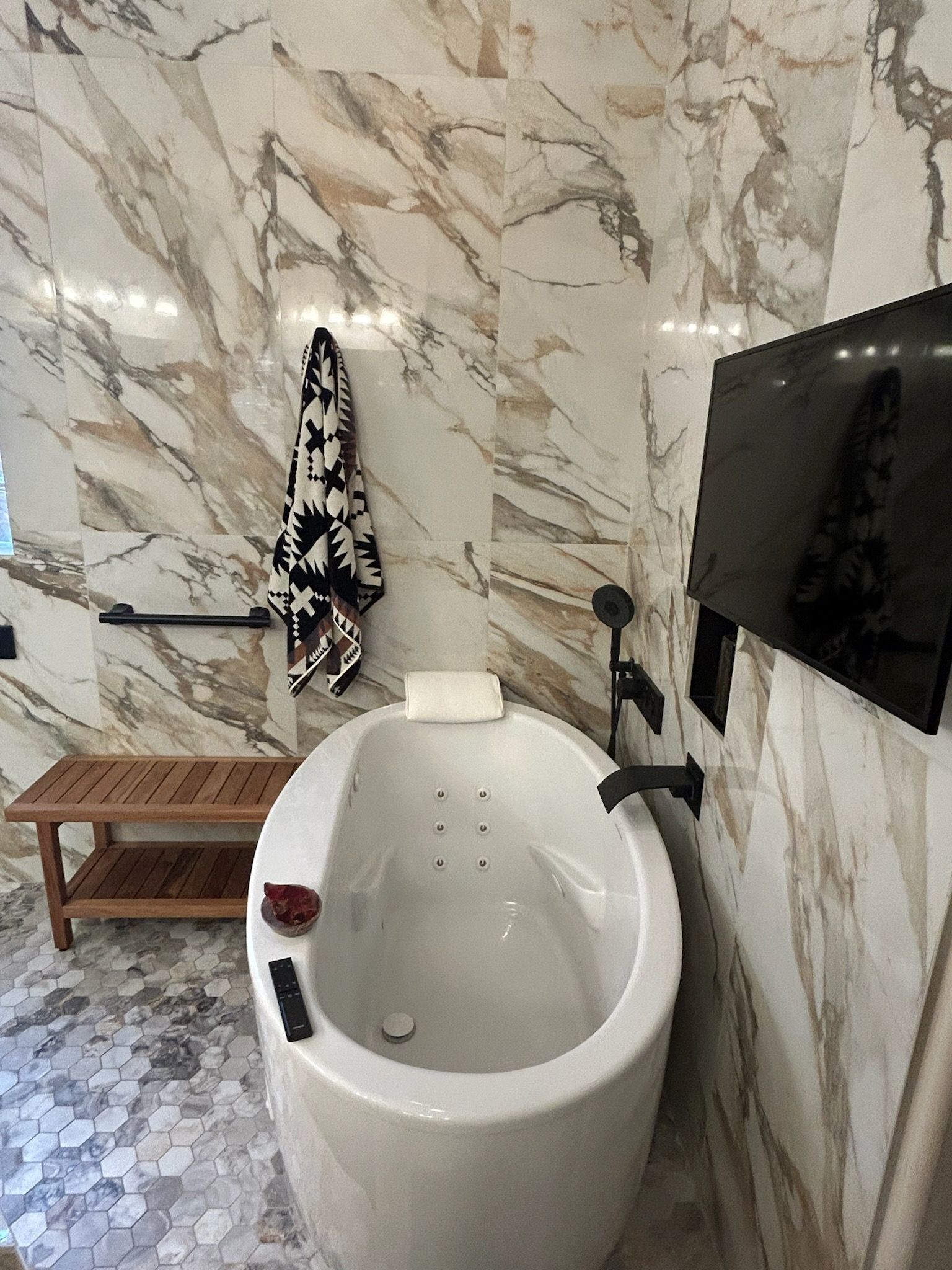 A bathroom with a bathtub and a television on the wall.