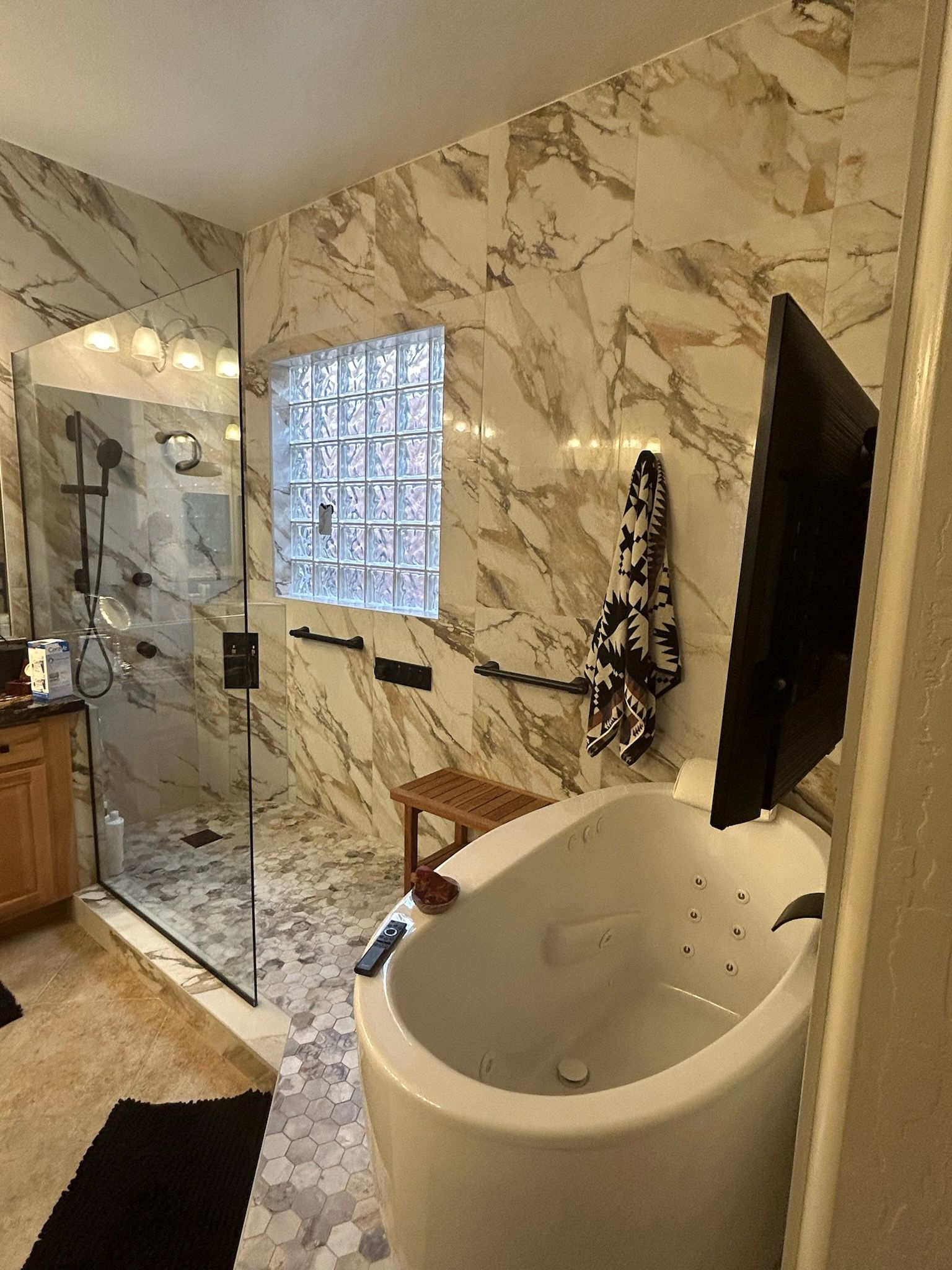 A bathroom with a tub , shower , and television.