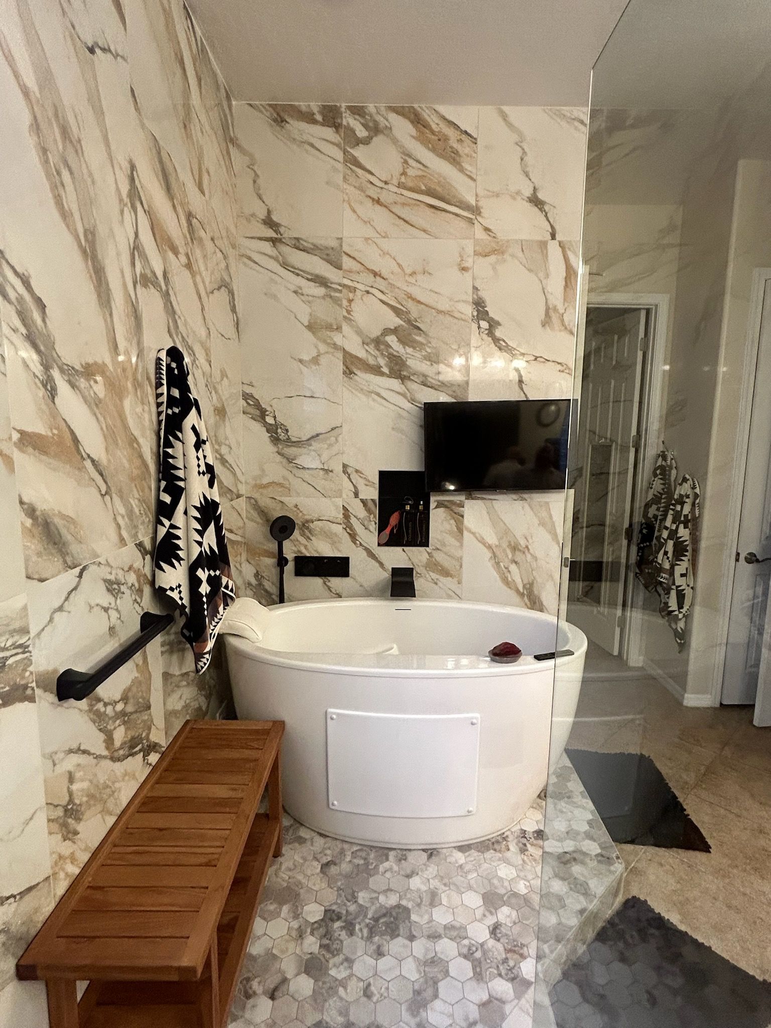 A bathroom with a large tub and marble walls.