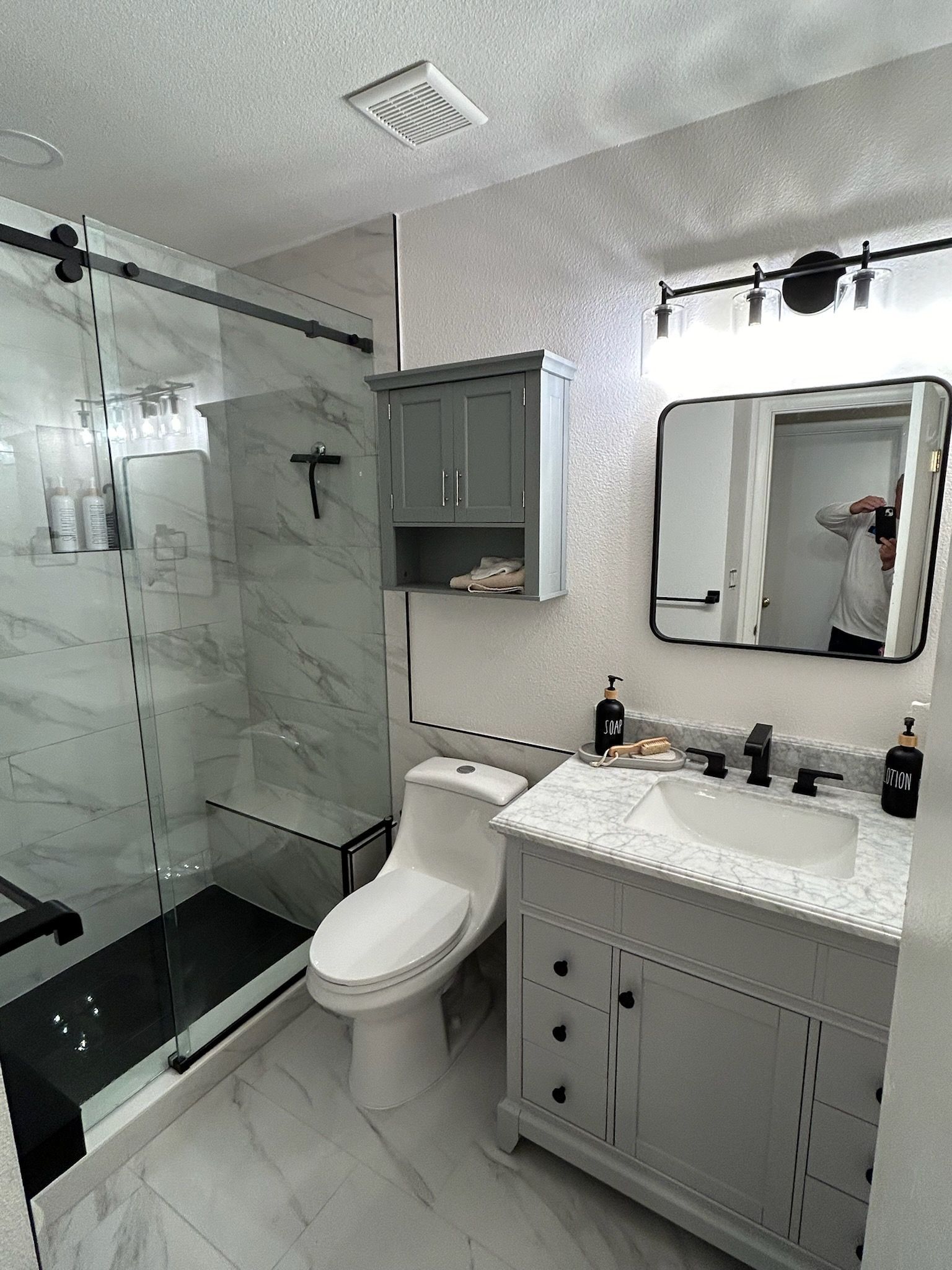 A bathroom with a toilet , sink , shower and mirror.