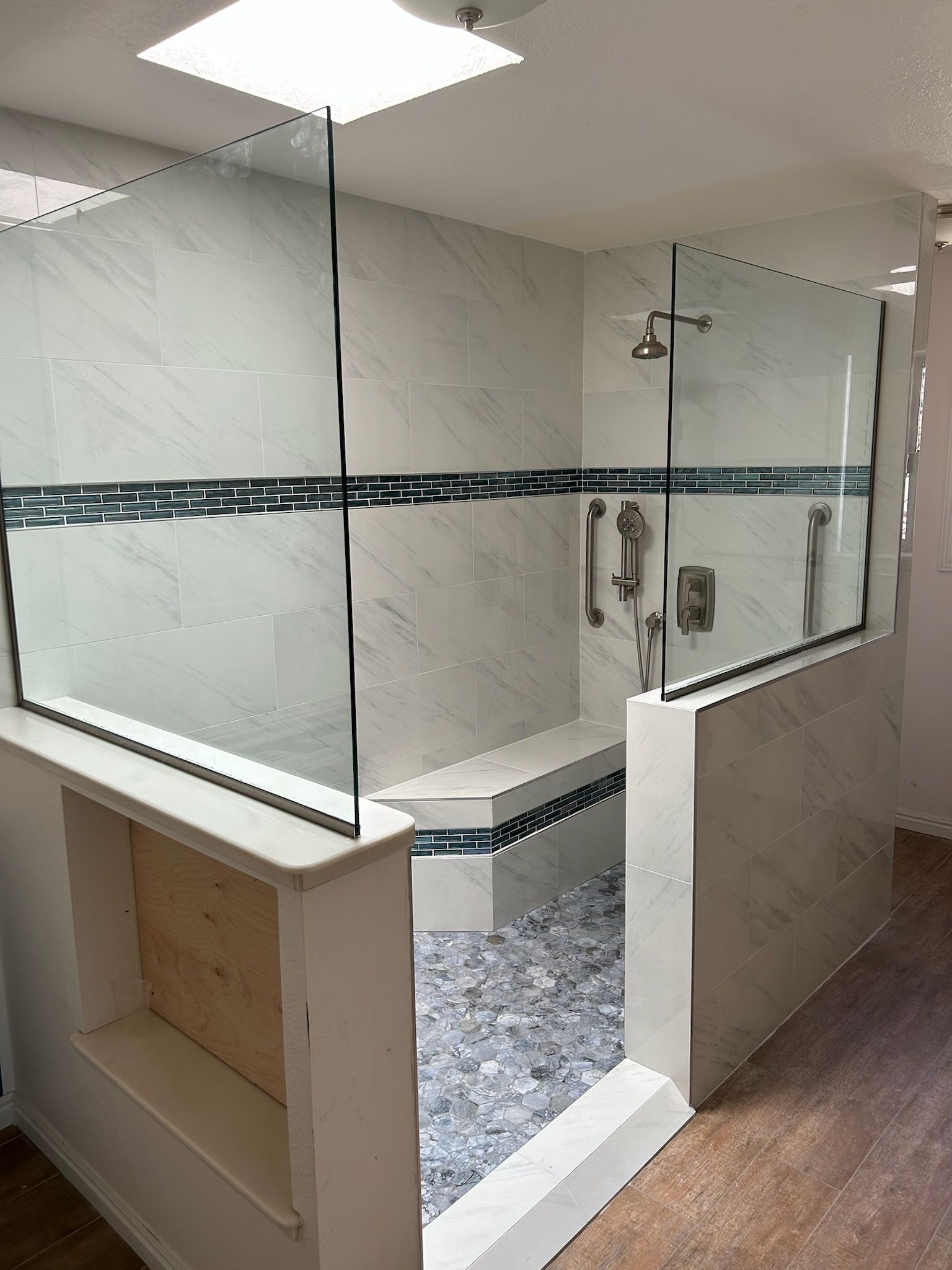 A bathroom with a walk in shower and a bench.
