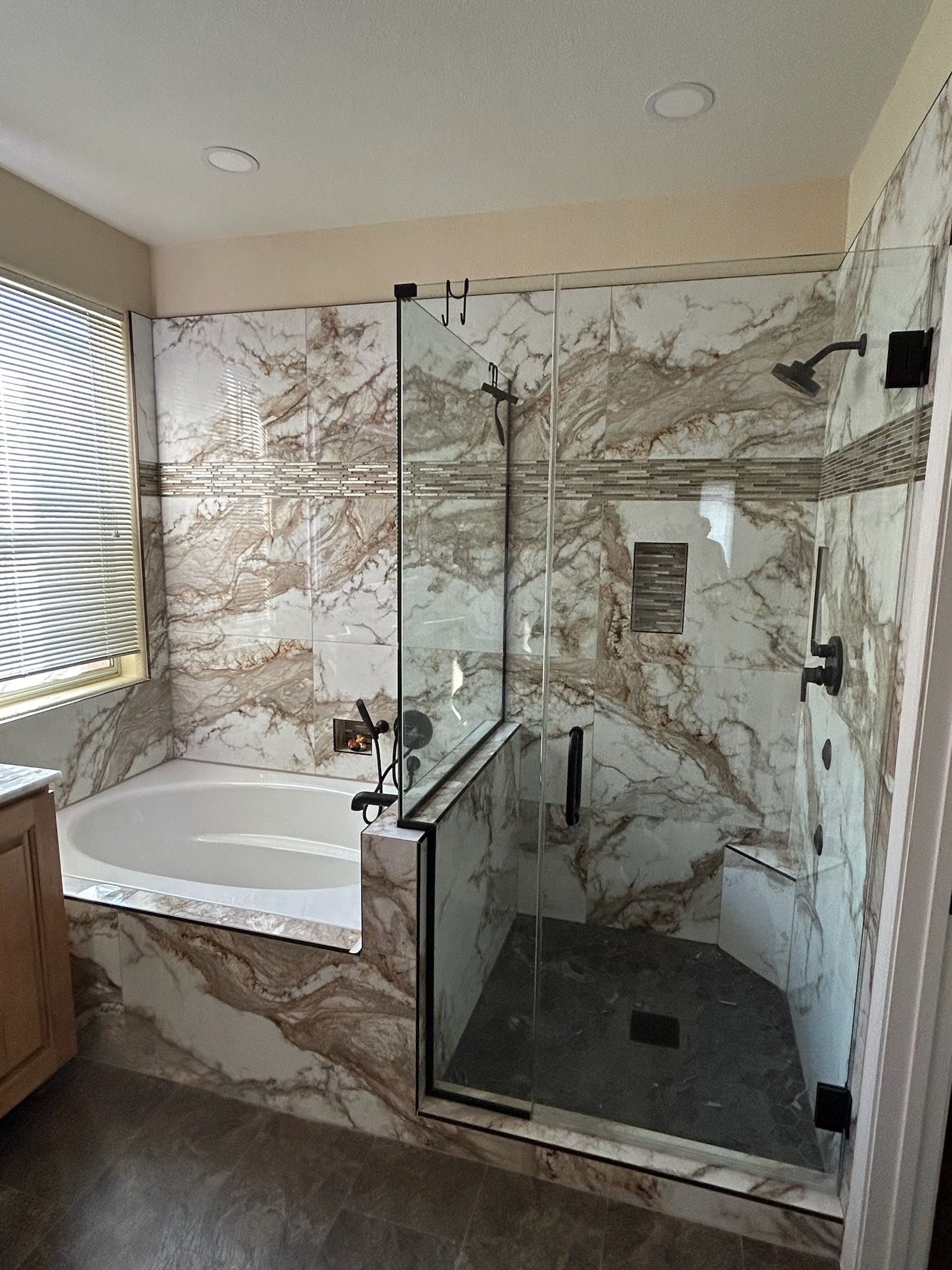 A bathroom with marble walls , a tub and a walk in shower.