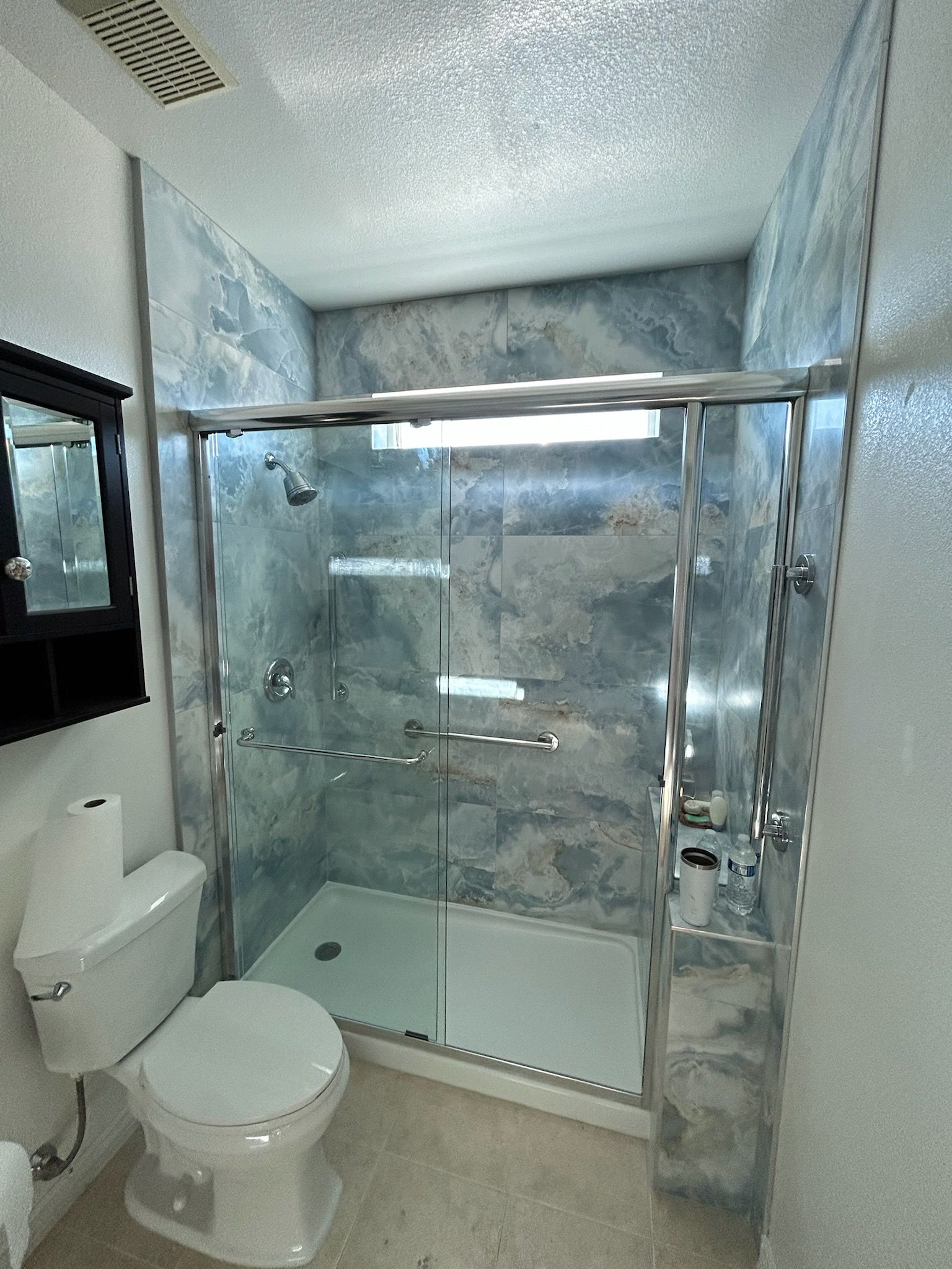 A bathroom with a toilet , shower and mirror.
