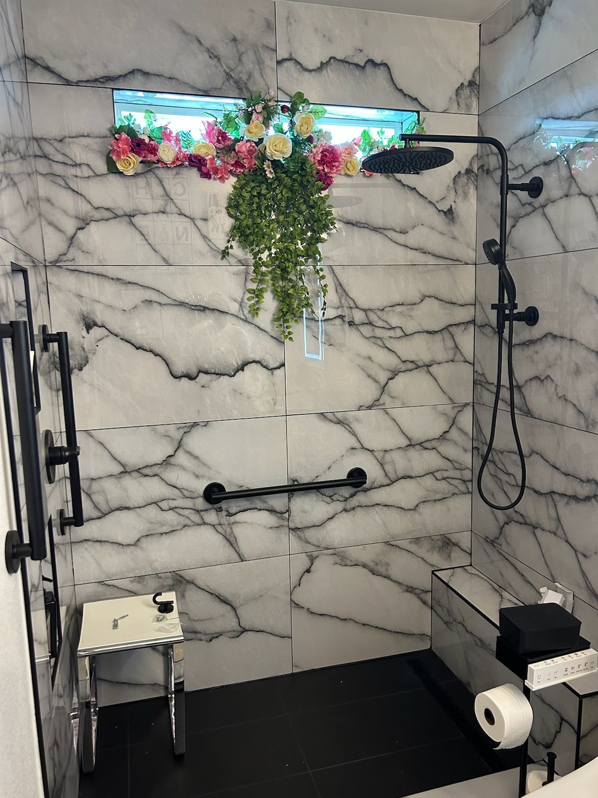 A bathroom with a walk in shower and a window with flowers on it.