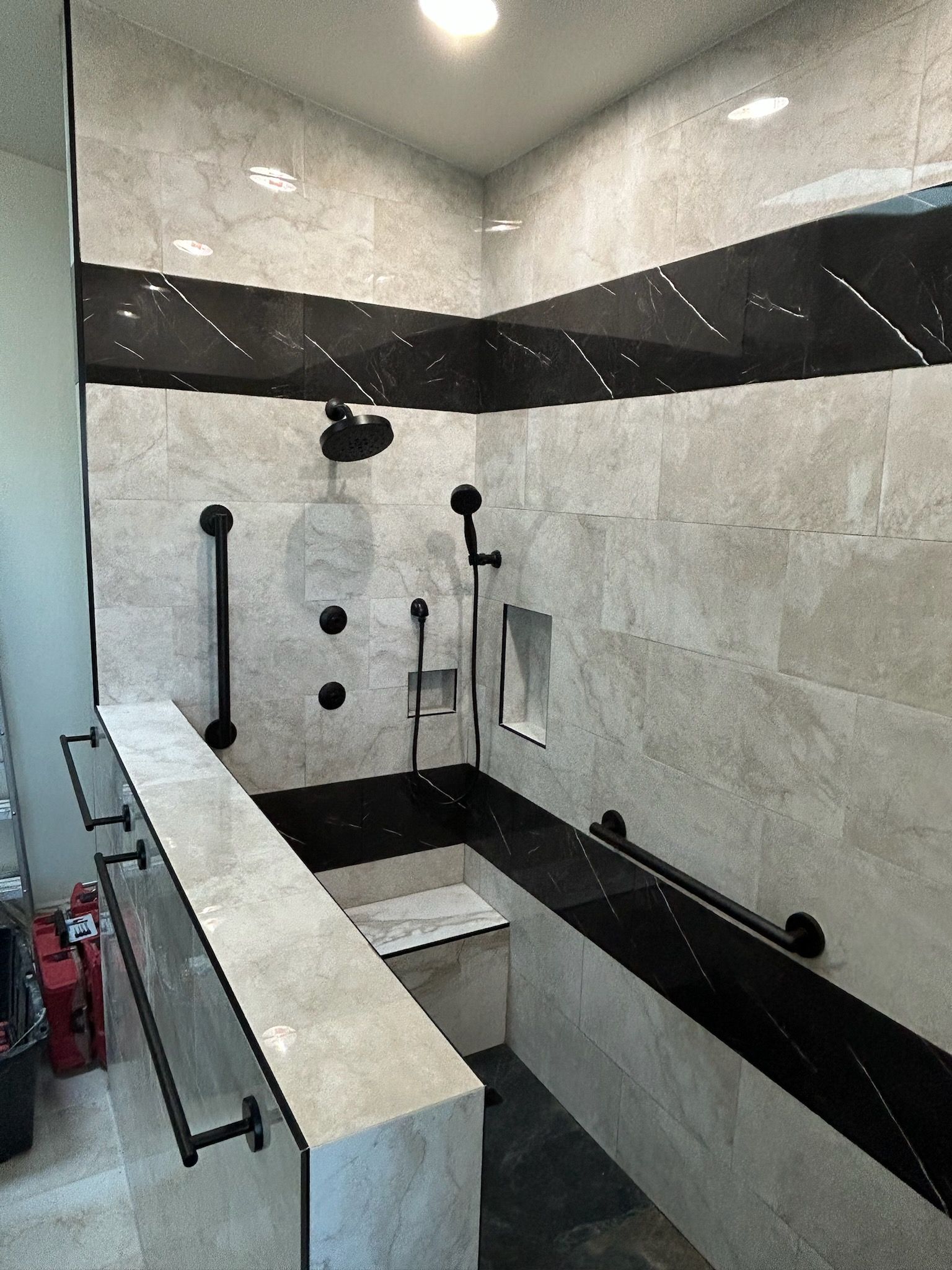 A bathroom with black and white tiles and a walk in shower.