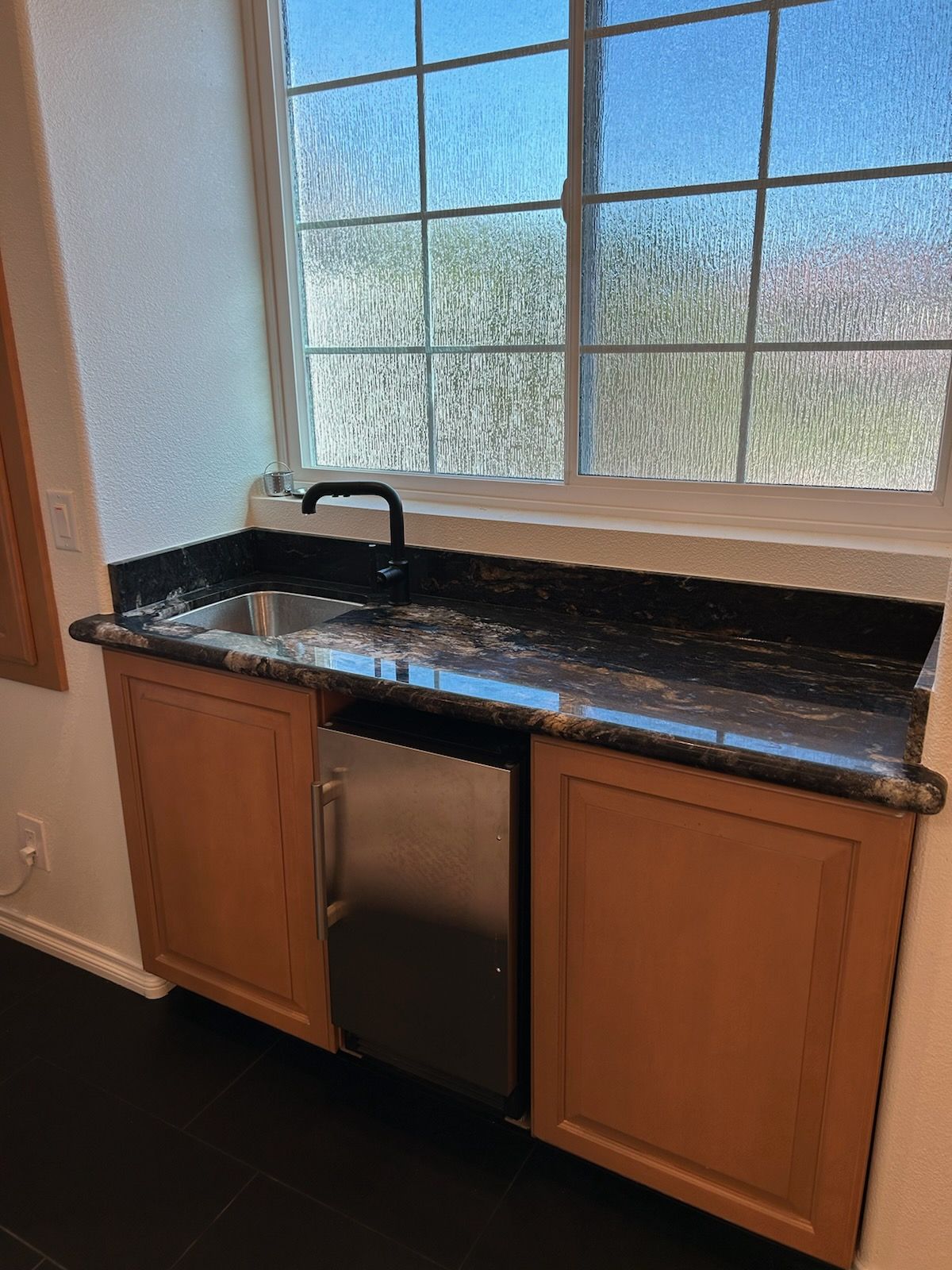 A kitchen with a sink , dishwasher , and window.