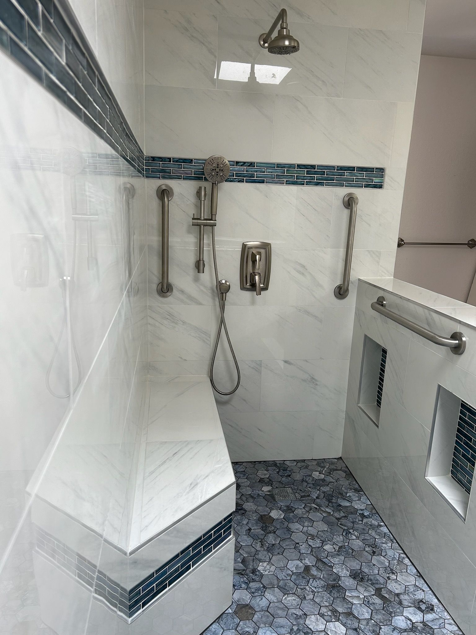 A bathroom with a walk in shower and a bench.
