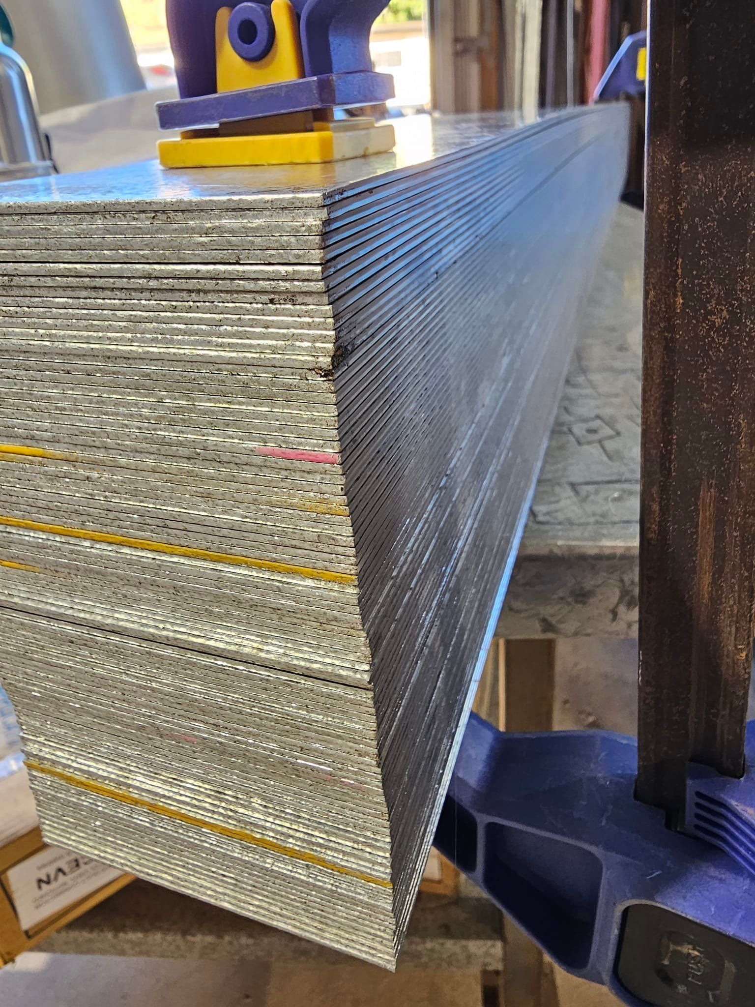 Stack of Corrugated Metal Sheets Clamped to a Workbench — Cumming Airconditioning & Sheetmetal in Ryan, QLD