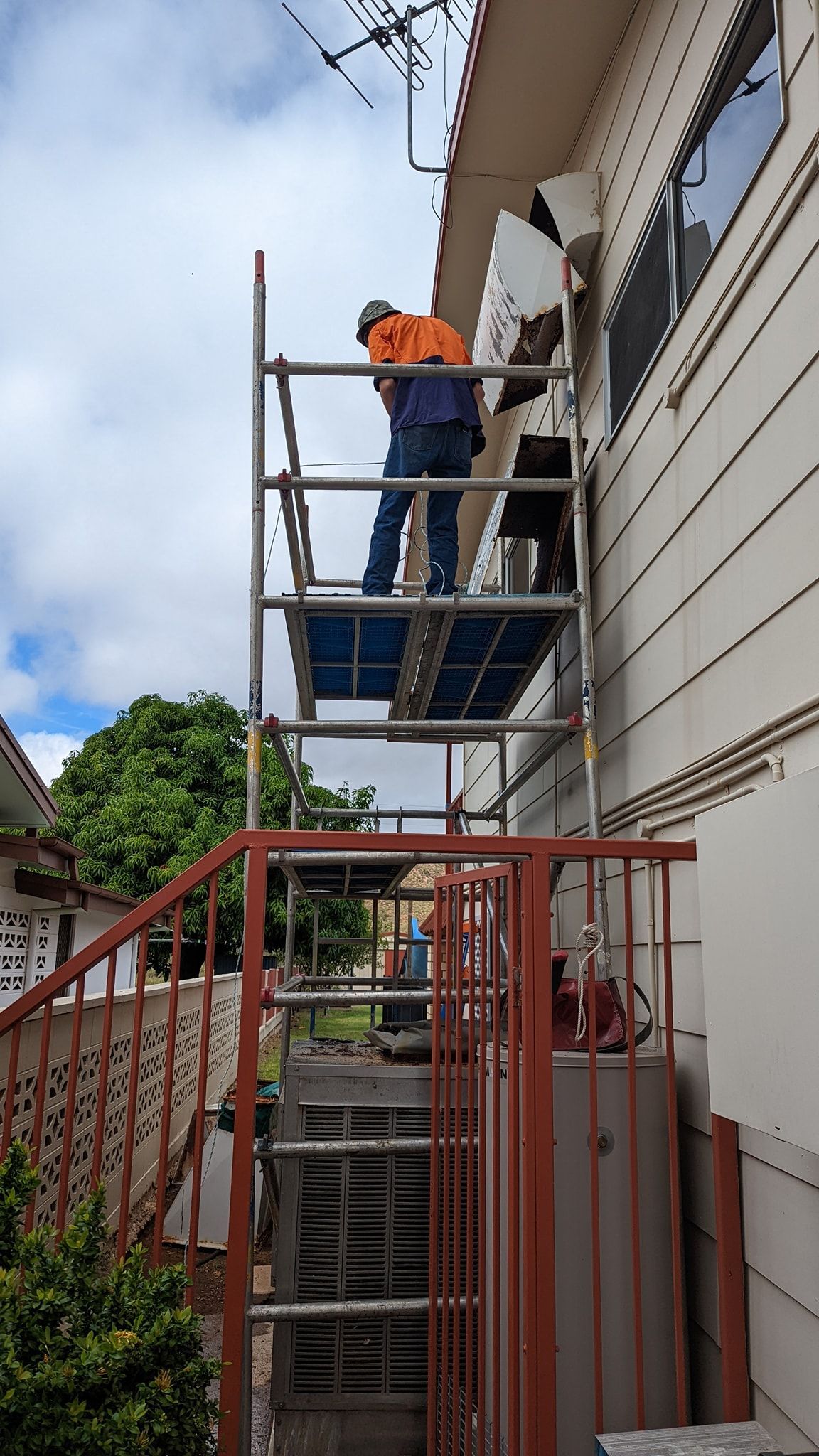 Person on Scaffolding Beside a House, Wearing Safety Gear — Cumming Airconditioning & Sheetmetal in Ryan, QLD