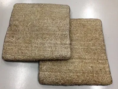 Two Square, Woven Fiber Seat Cushions, Stacked on a Gray Surface — Cumming Airconditioning & Sheetmetal in Ryan, QLD