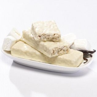 White-coated protein bars and marshmallows on a white plate, with a vanilla bean next to them.