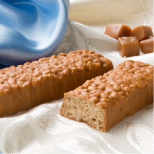 Two caramel-coated candy bars on white fabric, with a blue satin cloth and caramel squares.