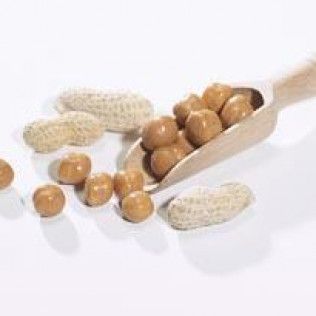 Peanuts in a shell and peanut candies spilling from a wooden scoop.
