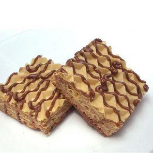 Two square cream-filled wafers with chocolate drizzle on a white surface.