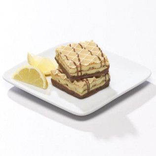 Two layered, square wafers with chocolate drizzle and lemon slices on a white plate.