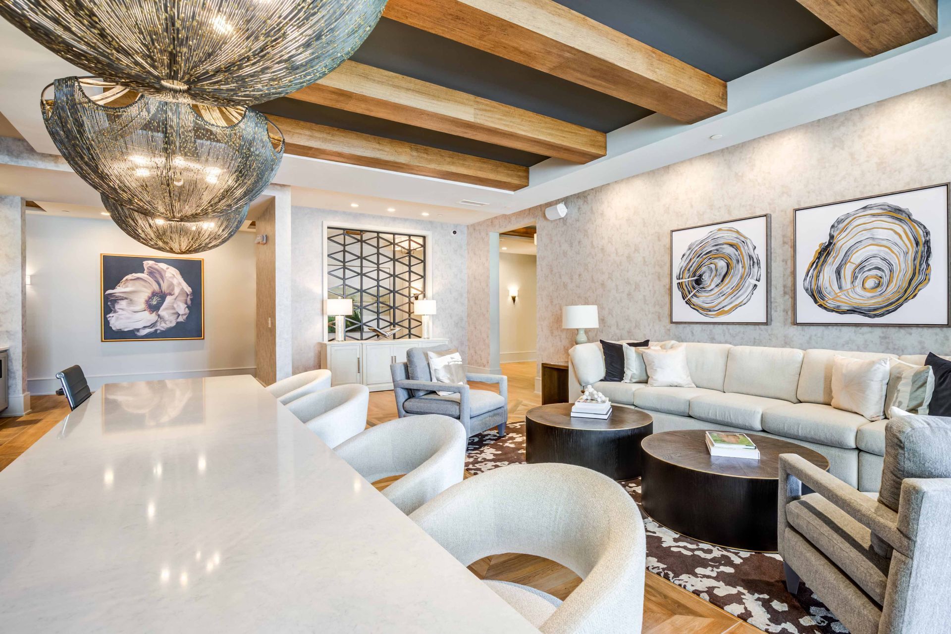 Lounge room with light-colored sofa, round coffee tables, and artwork; a large chandelier hangs overhead.