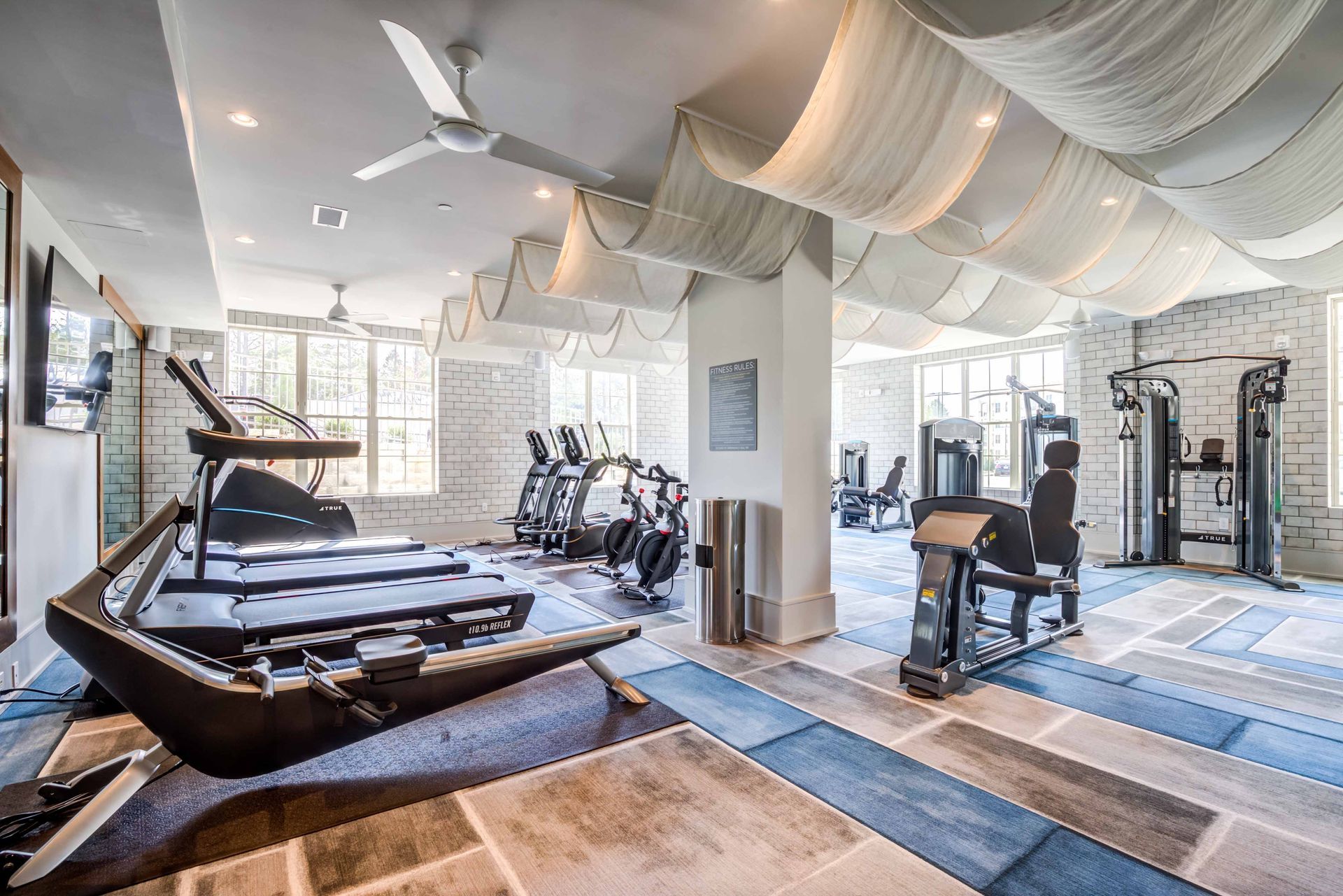 Gym with various workout machines, white brick walls, and a decorative ceiling.