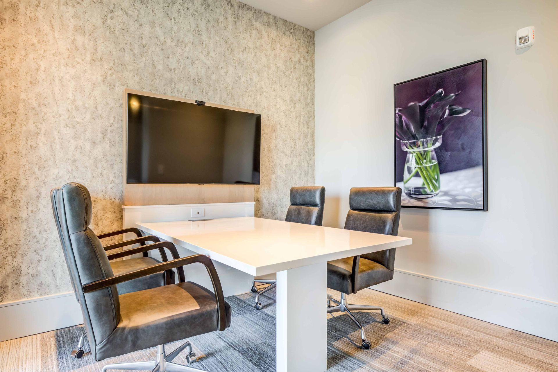 Meeting room with table, chairs, TV screen, and artwork on the wall.