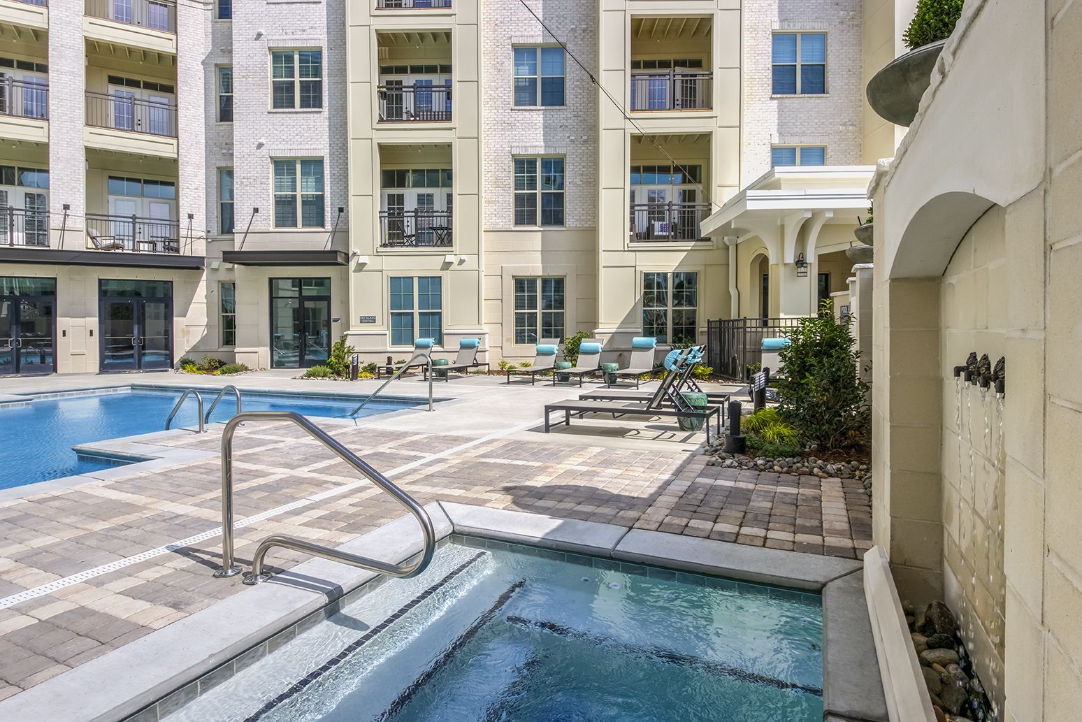 Pool and spa area with building, patio furniture, and fountain.