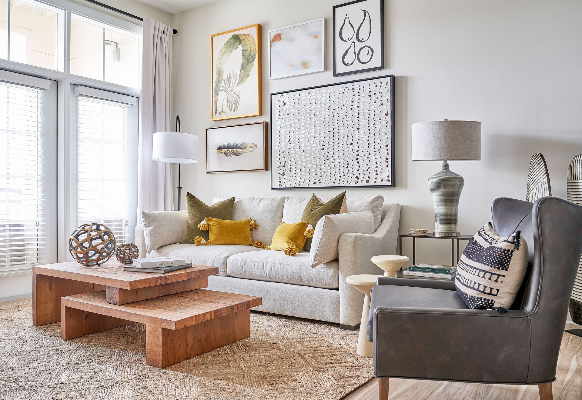 Living room with sofa, artwork, coffee table, and an armchair. Neutral color palette with natural textures.