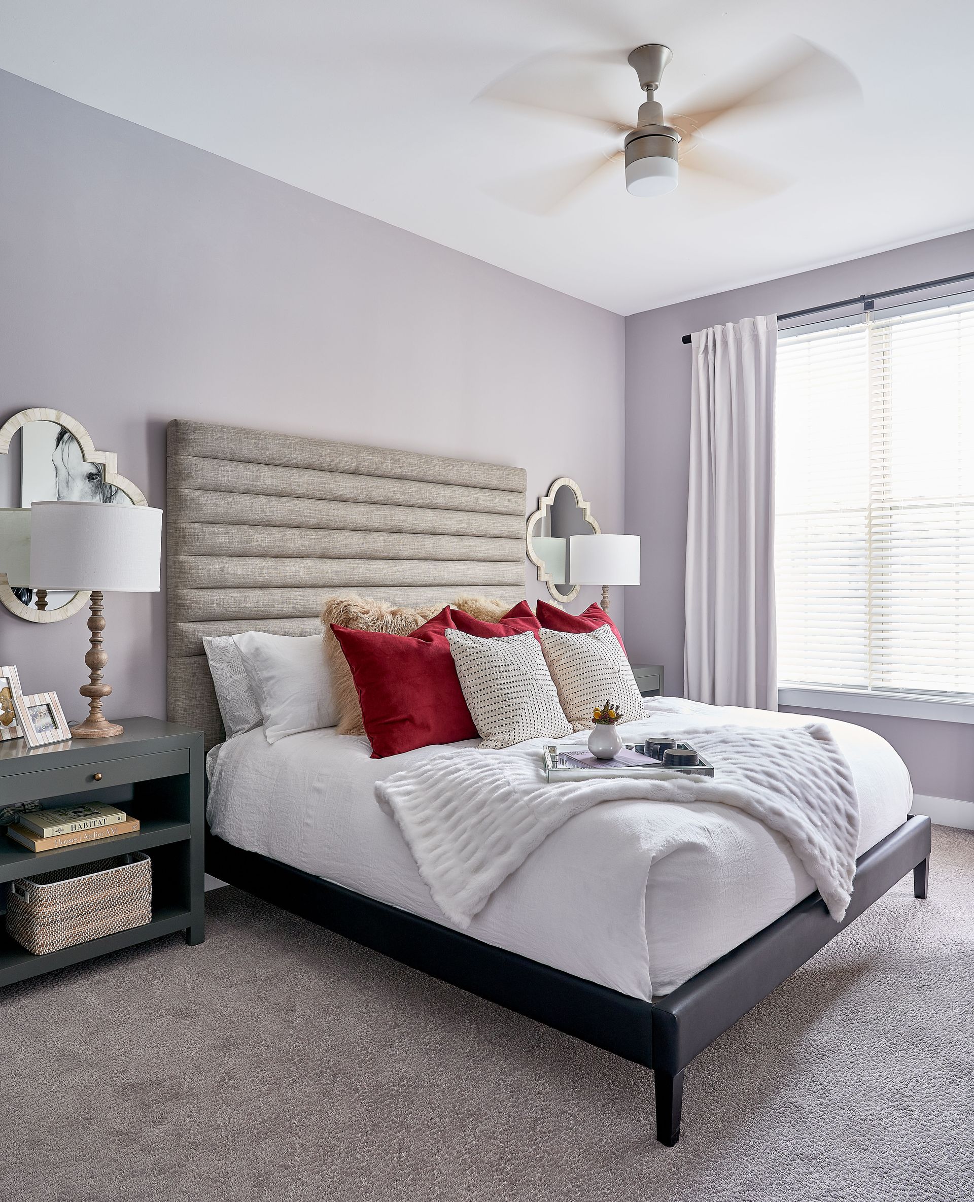 Bedroom with lavender walls, upholstered headboard, white bedding, gray nightstand, and ceiling fan.