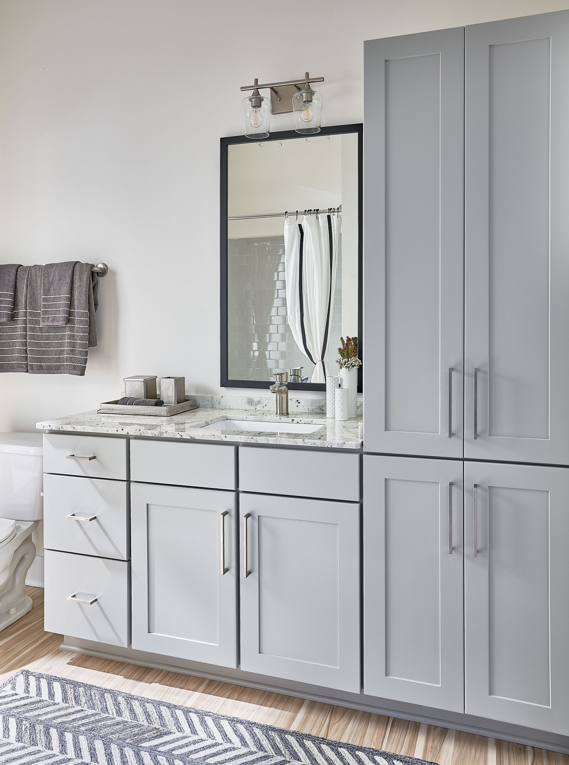 Bathroom with light gray cabinets, white countertop, and large mirror.