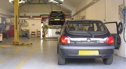 A small Ford Fiesta in a garage waiting to be serviced