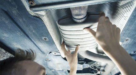 A mechanic working on a car exhaust