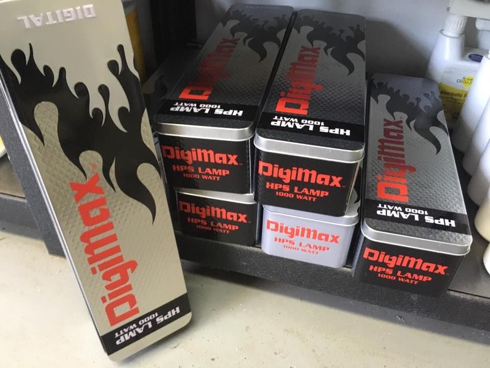 Boxes of DigiMax HPS lamps stacked on a shelf. The boxes are black, with red and white text.
