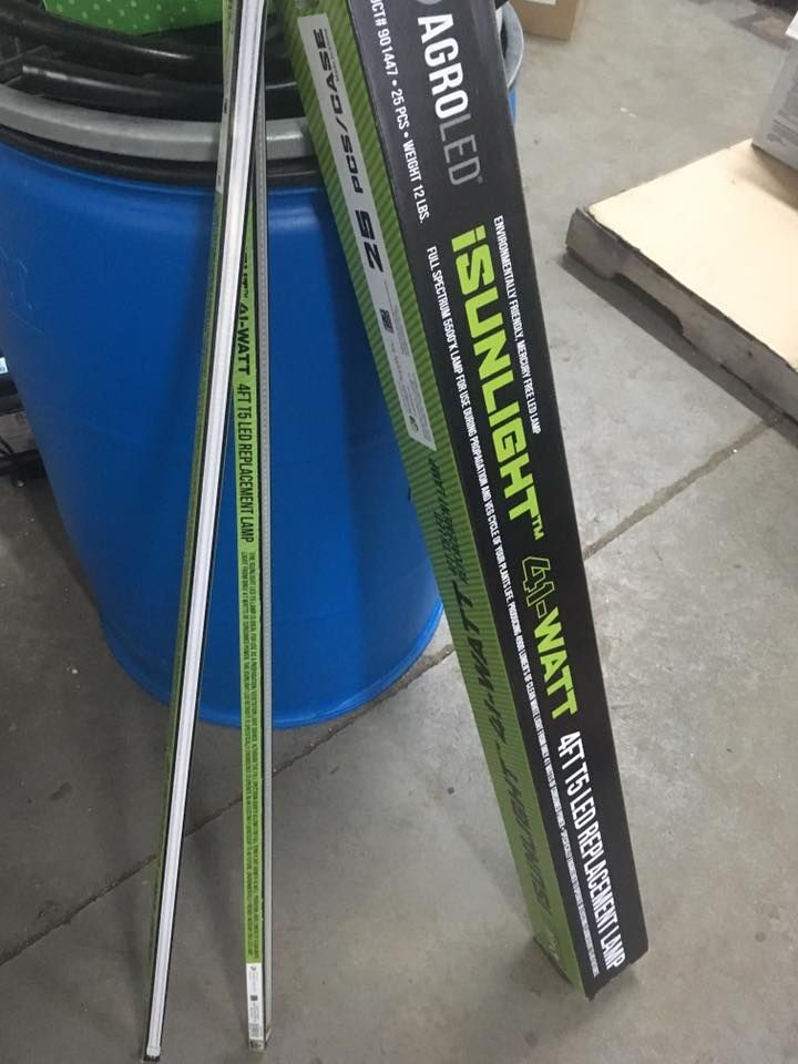 Two LED grow light tubes next to a box. Box reads 