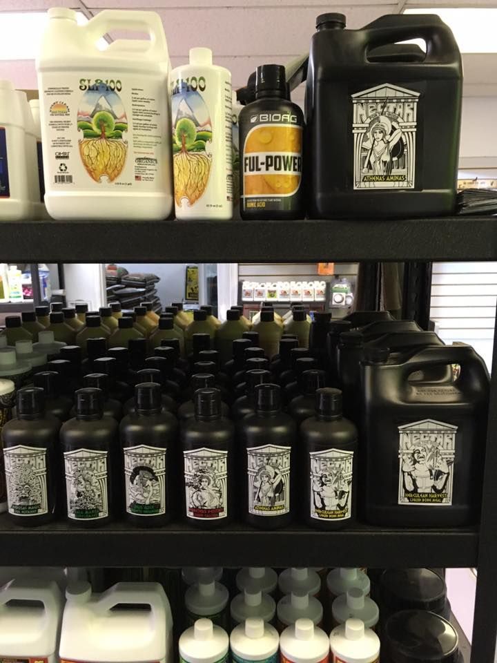 Shelves stocked with various plant nutrient bottles, mostly black with white labels.