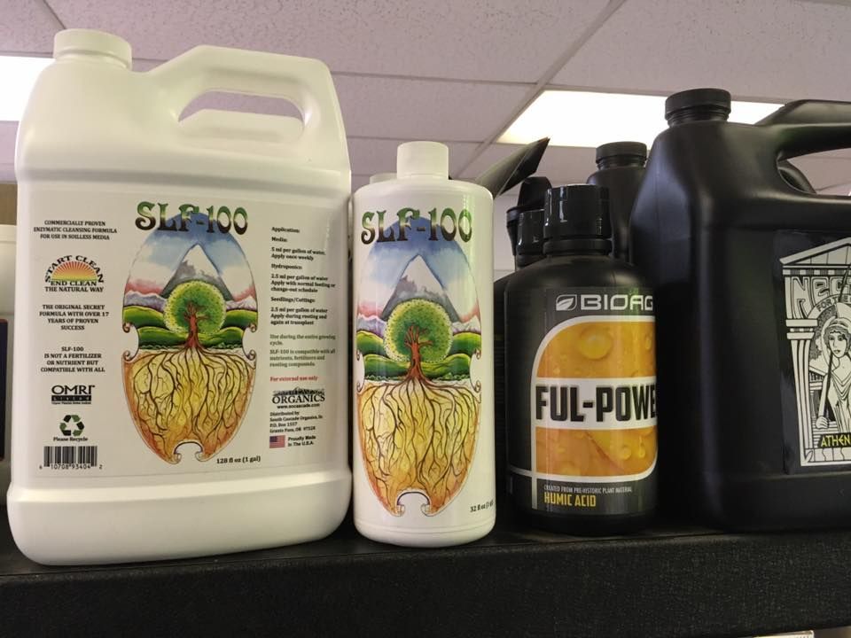Several liquid plant nutrient bottles on a shelf, including two SLX-100 and a Ful-Power container.