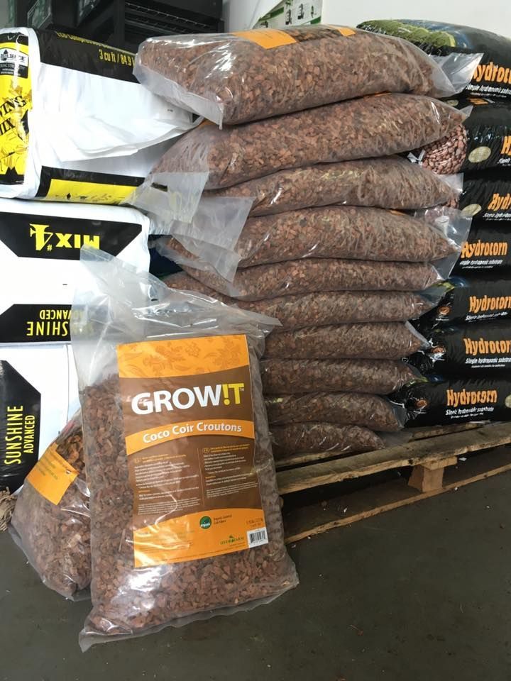 Bags of GrowIt coco coir stacked on pallets. Other gardening supplies are visible.