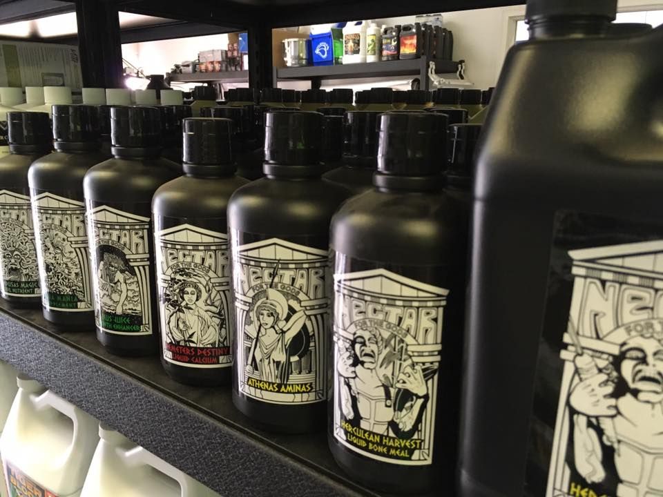 Rows of black bottles with white labels on a shelf. The labels depict figures and scenes.