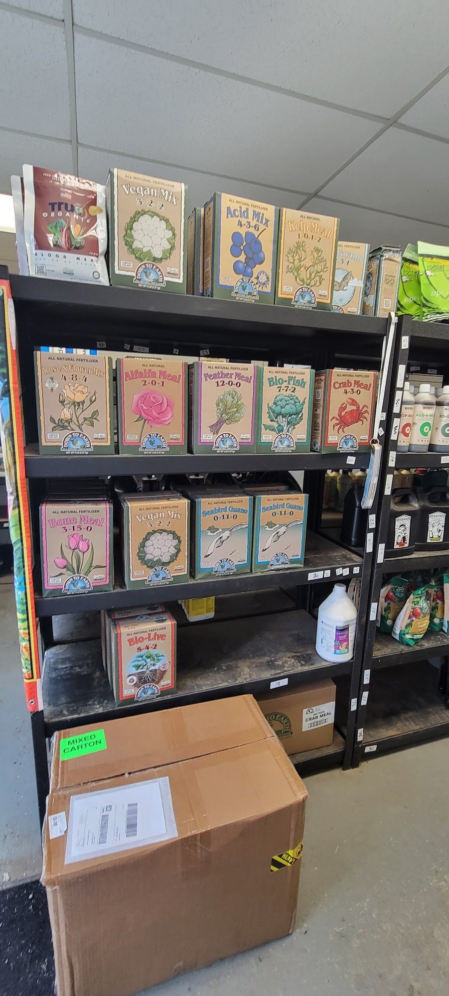 Shelves stocked with various seed packets in a store. Cardboard box is on the bottom shelf.