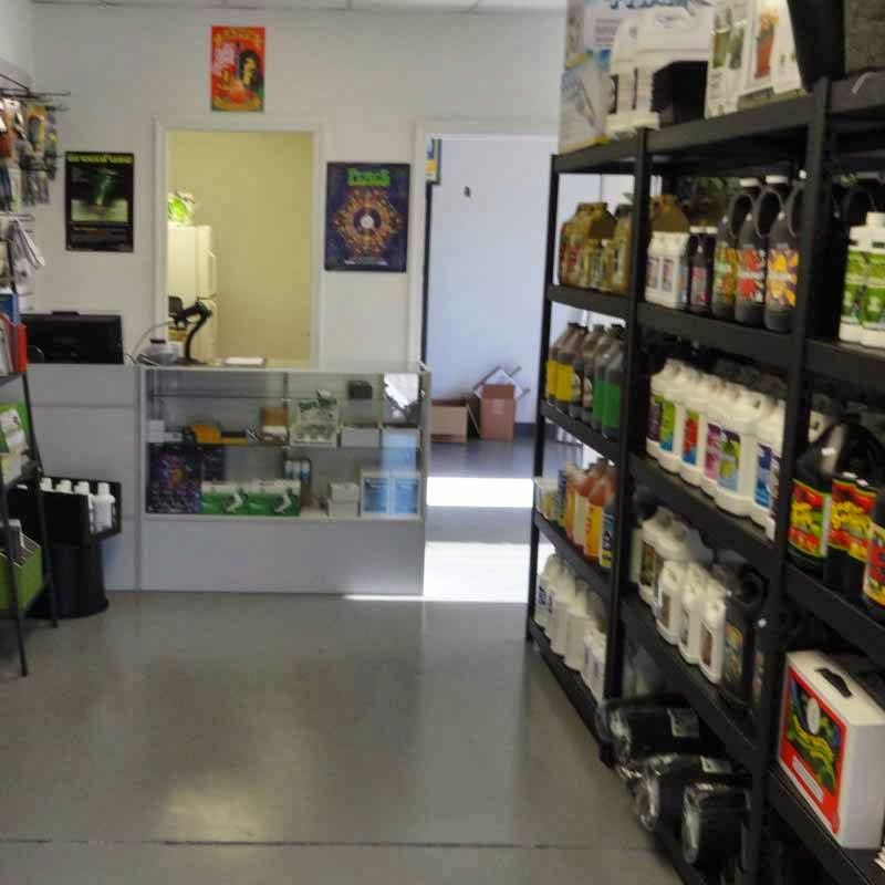 Inside of a grow shop with shelves of plant nutrients, a check-out counter, and open doorways.