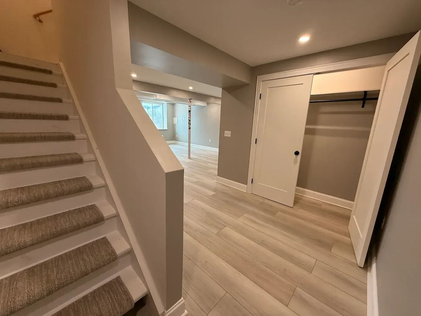 Staircase leading down to a hallway with a closet on the right and a room in the distance.