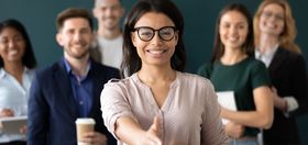 Professional team standing together as an employee extends a handshake, representing business growth