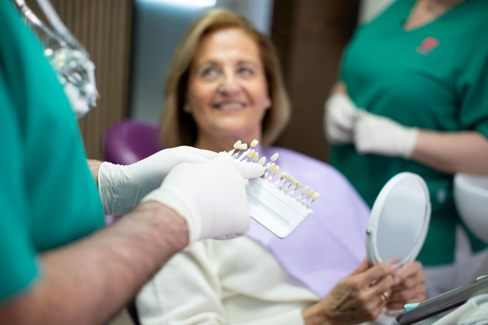 A dentist and a patient are selecting the shade for dental implants in a dental clinic setting. A dentist and a patient are selecting the shade for dental implants in a dental clinic setting.