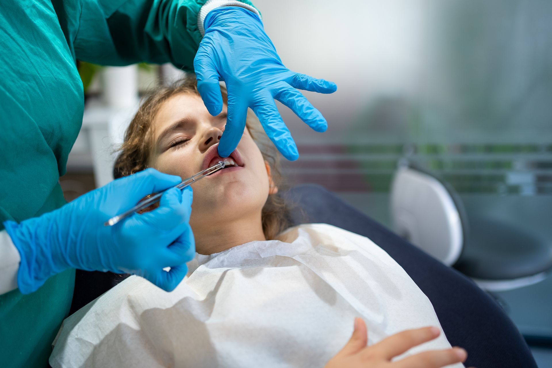 Dentist Checking Girl's Tooth | San Diego, CA - San Diego Center for Oral and Maxillofacial Surgery Dentist Checking Girl's Tooth | San Diego, CA - San Diego Center for Oral and Maxillofacial Surgery