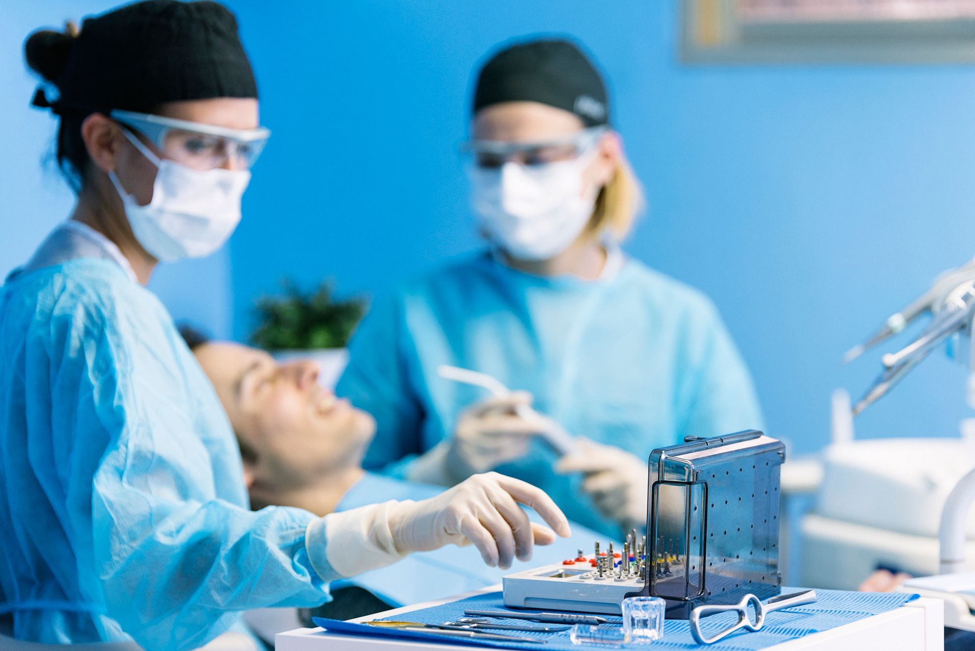 Two female oral surgeons are doing an operation on a male patient.