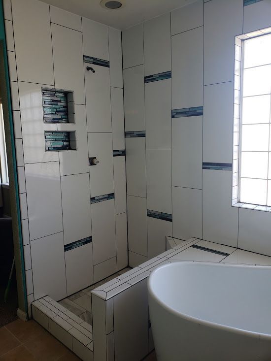 A bathroom with a tub , shower , and window.